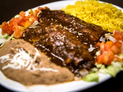 Pollo Mole (Chicken Mole) is Chicken Breast Simmered in an Original Puebla Mole Sauce Made with Chili Poblano Peppers, Almonds, Peanuts and Spices, Gently Spicy. Served with Rice and Refried Beans. Make substitutes below. OLE %%sitename%%