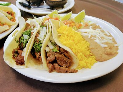 Steak Tacos >3 Marinated Strips of Beef Corn Tortilla Tacos with Fresh Onions, Cilantro, Rice and Refried Beans